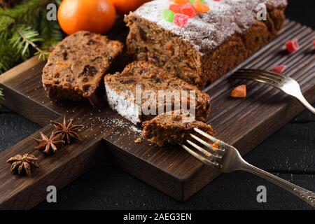 Tranches de gâteau aux fruits anglais traditionnel avec des fruits confits servi avec les clémentines et la badiane sur oak board libre Banque D'Images