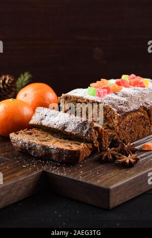Anglais savoureux fruits gâteau décoré avec des fruits confits servi avec des clémentines sur oak board copyspace closeup Banque D'Images