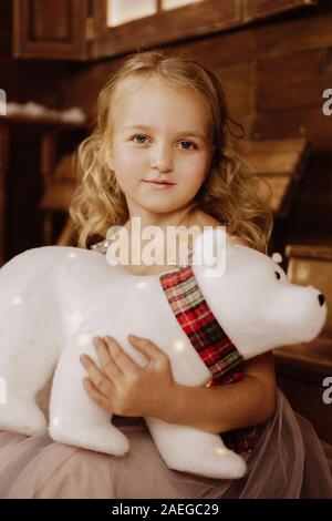 Little baby girl toddler sitting avec ours polaire blanc heureux sur fond de bois Banque D'Images