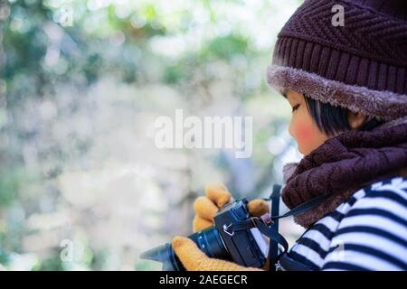 Portrait of a cute little girl in Wool hat de prendre une photo avec appareil photo numérique sur le climat est froid sur fond flou, photographie concept Banque D'Images