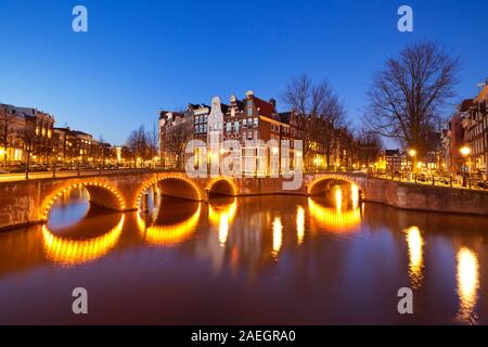 Ponts sur un carrefour de canaux dans la ville d'Amsterdam, les Pays-Bas dans la nuit. Banque D'Images