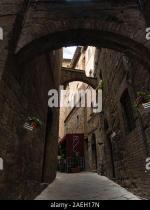 Les détails architecturaux de l'époque médiévale en pierre et brique maisons dans un passage étroit, à Volterra, Toscane, Italie Banque D'Images