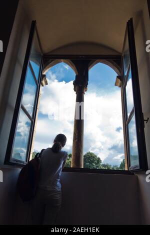 Fille à la fenêtre avec une vue à l'intérieur du palais a priori à Volterra, qui est la ville la plus ancienne des assemblées en Toscane, Italie Banque D'Images