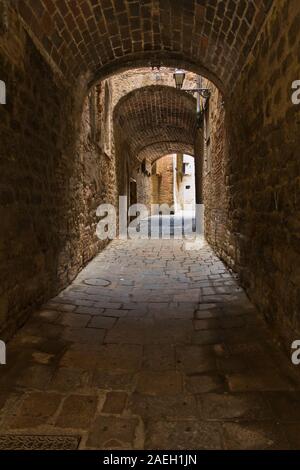 Les détails architecturaux de l'époque médiévale en pierre et brique maisons dans un passage étroit, à Volterra, Toscane, Italie Banque D'Images