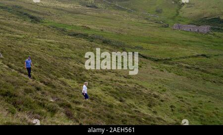Portrait de touristes dans le champ de ruines du bâtiment en arrière-plan, la tête d'Achill randonnée pédestre, Quille, Comté de Mayo, République d'Irlande Banque D'Images