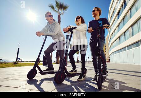 Trois meilleurs amis jeunes de 20 ans à 30 ans, fille et gars passent du temps à l'extérieur réunis ensemble à conduire sur un scooter électrique moderne véhicule terrestre Banque D'Images