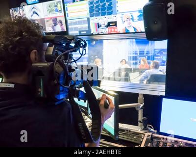 PARIS, FRANCE- novembre 2019, Circa. L'homme de l'appareil photo dans le local technique avec console de mixage audio, ordinateurs, TV LED, écrans et matériel d'enregistrement en studio Banque D'Images