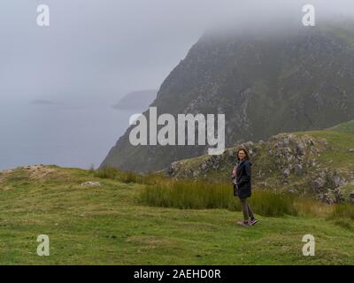 Femme debout par Cliff, l'île d'Achill, Comté de Mayo, Irlande Banque D'Images