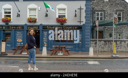 Woman standing in front of bar, Tante Lena's Bar, Adare, comté de Limerick, Irlande Banque D'Images