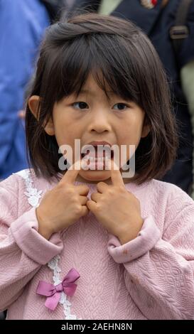 Japanese girl making a face en tirant sur sa bouche, Tokyo, Japon Banque D'Images