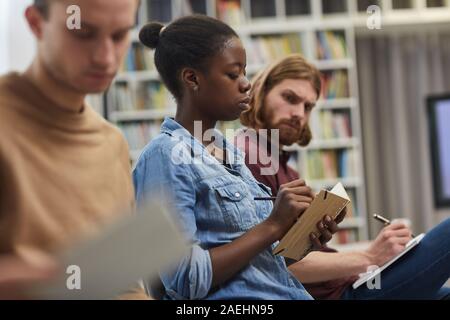 African woman et prendre des notes dans son calepin avec ses collègues lors d'une conférence Banque D'Images