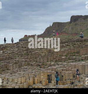 Les touristes marcher sur les roches basaltiques, Chaussée des Géants, le comté d'Antrim, Irlande du Nord, Royaume-Uni Banque D'Images