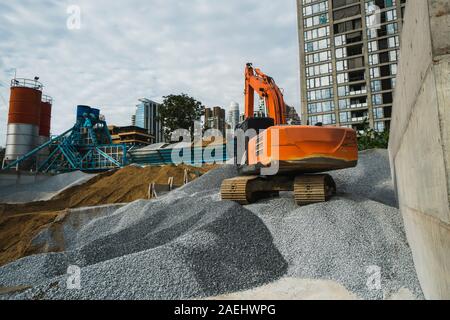 Grande pelle orange travaille sur un gravier sur chantier de construction. Détails de l'excavateur industrielle. Grand debout sur une excavatrice collines de gravier et Banque D'Images