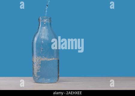 Le flacon en verre avec de l'eau, on verse de l'eau. Banque D'Images