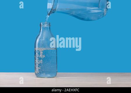 Le flacon en verre avec de l'eau, on verse de l'eau. Banque D'Images