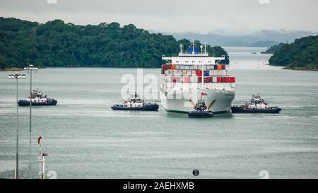 Porte-conteneurs Safmarine Nokwanda (surround) par le Canal de Panama les remorqueurs dans le lac Gatun attendent pour entrer l'Agua Clara serrures. Banque D'Images