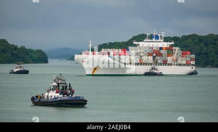 Porte-conteneurs Safmarine Nokwanda (surround) par le Canal de Panama les remorqueurs dans le lac Gatun attendent pour entrer l'Agua Clara serrures. Banque D'Images