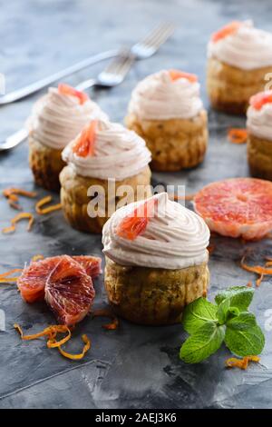 Des bonbons sans sucre sain. Fruits secs muffins au fromage à la crème et le glaçage orange sanguine sur fond sombre libre Banque D'Images
