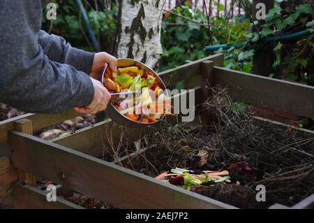 L'approvisionnement de compost écologie - recyclage des déchets de cuisine en composteur. L'homme jette les restes de légumes de la planche à découper. Tue l'environnement Banque D'Images