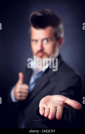 Un portrait d'homme barbu avec les iroquois portant costume couvrant montrant ouvrir Palm à l'appareil photo. Les gens et les émotions concept Banque D'Images