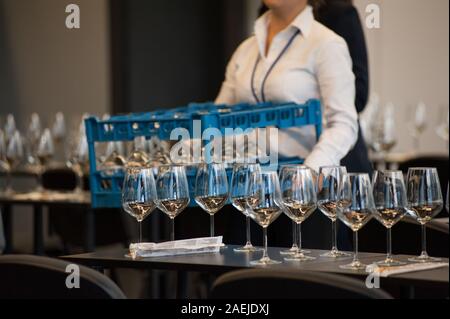 Jeu de serveuse les tables avec crystal gobles pour un atelier de dégustation de vin. Service de restauration et le personnel de salle à manger au travail. Banque D'Images