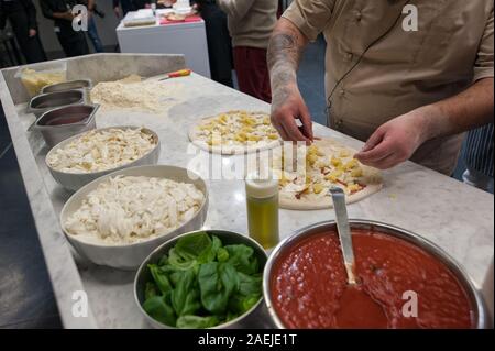 La préparation de Pizza Margherita sur une en haut. Morceaux de mozzarella met pizzaiolo et de pommes de terre sur une pâte à pizza de matières premières. Banque D'Images