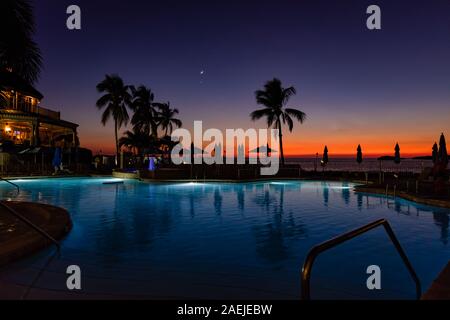 Fort Myers, Floride, USA - 28 novembre 2019 : magnifique coucher de soleil et de la Lune dans le ciel, vue de la piscine à débordement, d'un hôtel sur le golfe du Mexique un Banque D'Images