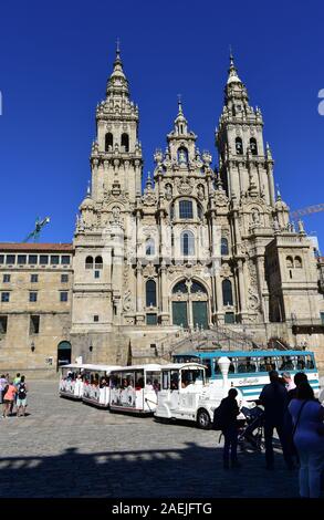 Cathédrale avec les pèlerins, les vieux bus et train touristique. Voir à partir de la Praza do Obradoiro avec ciel bleu. Santiago de Compostela, Espagne. Jul 28, 2019. Banque D'Images