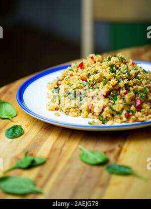 Des végétaliens (vegan) Salade de boulgour céréales avec des légumes frais, épinards, avocat, épices et huile d'olive. Eco Bio santé concept alimentaire. Banque D'Images