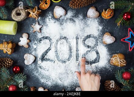 Bonne Année 2018 écrit sur la farine et les décorations de Noël Gingerbread cookies sur pierre sombre arrière-plan. Carte de Noël, carte de voeux Nouvel An Banque D'Images