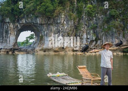 Guilin, Chine - Août 2019 : les touristes détenteurs bâton de bambou avec des oiseaux et des cormorans qui pose pour photo souvenir devant le monument d'éléphant Banque D'Images