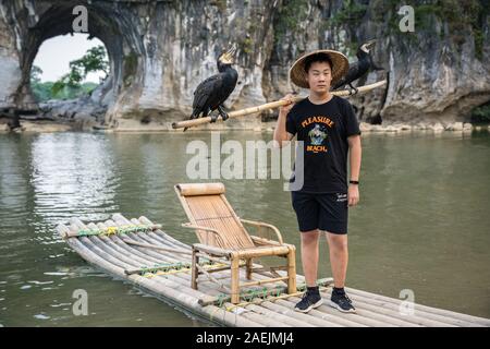 Guilin, Chine - Août 2019 : les touristes détenteurs bâton de bambou avec des oiseaux et des cormorans qui pose pour photo souvenir devant le monument d'éléphant Banque D'Images