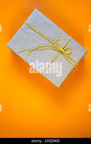 Boîte-cadeau enveloppé dans du papier recyclé attachées avec de la ficelle jaune, un cadeau ou un concept de livraison Banque D'Images