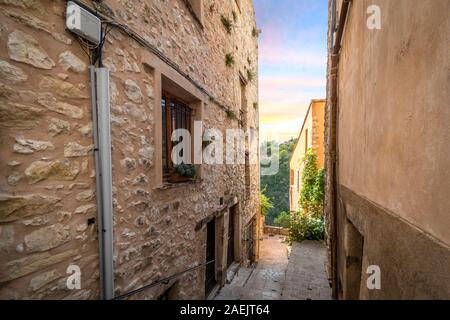 Le coucher du soleil et sur la montagne à travers une ruelle dans le village en pierre médiéval de Tourrettes sur Loup dans le sud de la France. Banque D'Images