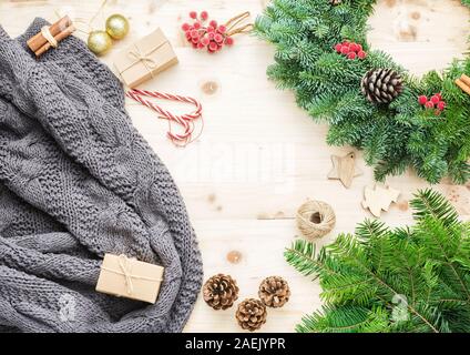 Vue de dessus de la couronne de Noël, branches de pin, présente sur la table en bois, eco tags et boîtes de papier brun, gris cosy throw blanket, selective focus Banque D'Images