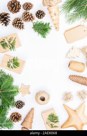 Cadre de Noël arrière-plan. Vue de dessus du sapin branhes brown, coffrets cadeaux, accessoires divers pour handmade présente des décorations en bois, pommes de pin, tags sur tableau blanc, copy space, selective focus Banque D'Images