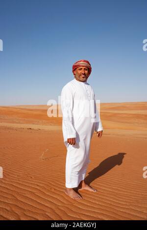 Bedouin en costume traditionnel se trouve dans le désert de sable, désert de Rimal Wahiba Sands, Oman Banque D'Images