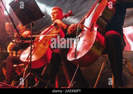Les concerts de violoncelle avec tableau de près. Vibrant rouge contexte lors de concert de rock Banque D'Images