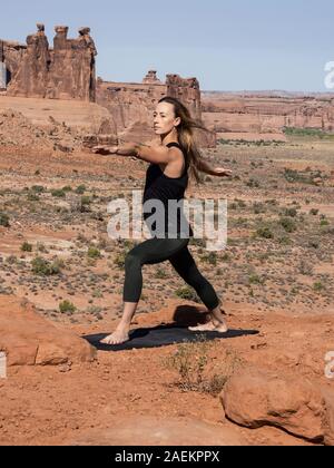 Jeune femme pratique le yoga à Montagnes La Sal oublier dans Arches National Park près de Moab, Utah. Dans l'arrière-plan sont le palais de Tours. Banque D'Images