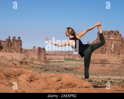 Jeune femme pratique le yoga à Montagnes La Sal oublier dans Arches National Park près de Moab, Utah. Dans l'arrière-plan sont le palais de Tours. Banque D'Images