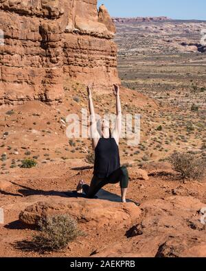 Jeune femme pratique le yoga à Montagnes La Sal oublier dans Arches National Park près de Moab, Utah. Dans l'arrière-plan sont le palais de Tours. Banque D'Images