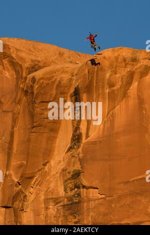 Un pas de géant vers le sommet de la face verticale de 400 pieds de la pierre tombale dans Kane Springs Canyon près de Moab, Utah. Remarque son ombre sur la falaise. Banque D'Images