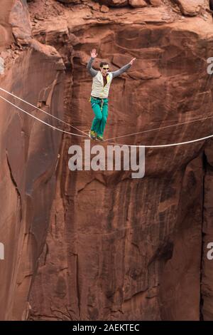 Un jeune homme slackline ou highlining des centaines de pieds au-dessus du Canyon de minéraux près de Moab, en Utah pendant un rassemblement highline. Banque D'Images