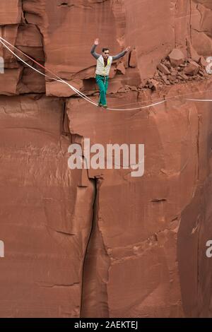 Un jeune homme slackline ou highlining des centaines de pieds au-dessus du Canyon de minéraux près de Moab, en Utah pendant un rassemblement highline. Banque D'Images