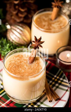 Une vue du haut vers le bas de deux verres de lait de poule et la cannelle garnie avec des bâtons de cannelle et l'anis étoilé et entouré d'ornements de Noël, des pommes de pin Banque D'Images