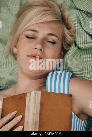 Femme couchée sur sac en champ et profiter de la lecture de livres. Banque D'Images