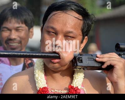 Passionnée Thai dévot taoïste chinois perce sa joue gauche avec un fusil pendant le Festival Végétarien de Phuket (neuf dieux Empereur Festival). Banque D'Images