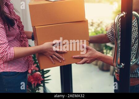 Femme qui reçoit de l'homme livraison de colis à la porte. Banque D'Images