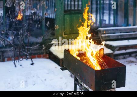 Sciage brûlant dans une arrière-cour à l'extérieur sur brasero en hiver, confortable winer holidays Banque D'Images