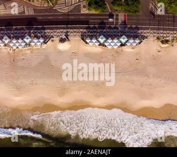 Vue du haut vers le bas sur la plage de Copacabana vide avec des bars de plage sur le boulevard avec le trottoir décoré et des vagues qui arrivent à lever tôt le matin Banque D'Images